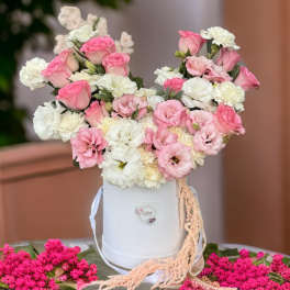 Pink and white flower arrangement in a white hatbox with ribbon