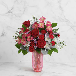 Red and pink mixed bouquet in a pink glass vase