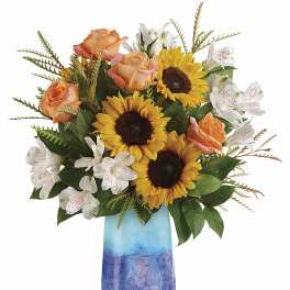 Sunflowers, peach roses, and white alstroemeria in a blue vase