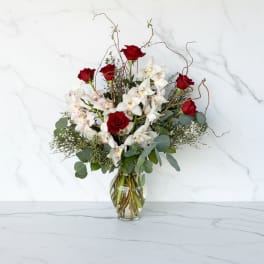 Red roses and white orchids in a clear glass vase