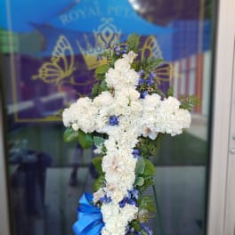 White floral cross arrangement with blue accents and a blue ribbon