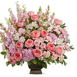 Pink roses and mixed blooms arranged in a dark vase