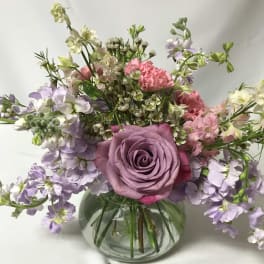 Lavender rose bouquet with pink and white flowers in a round glass vase