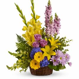 Mixed bouquet in a wicker basket with yellow, purple, and pink flowers