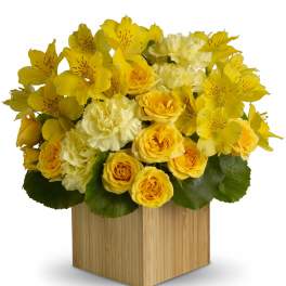 Yellow roses and alstroemeria in a wooden cube vase