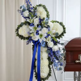 White and blue funeral spray with lilies and roses on a stand