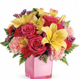 Pink roses and yellow lilies arranged in a pink vase