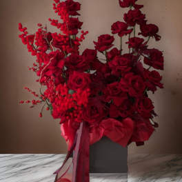 Red rose arrangement in a gray box with ribbon