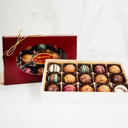 Box of assorted chocolate truffles with a red gift box behind it
