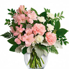 Pink and white carnations and alstroemeria arranged in a round clear glass vase
