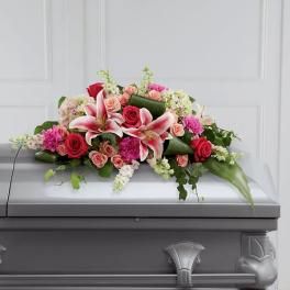 Floral casket spray with pink lilies and red roses