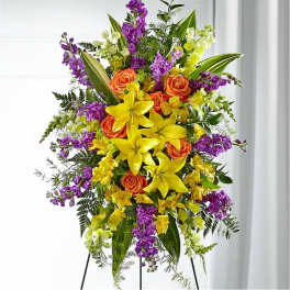 Tall floral standing spray with yellow lilies, orange roses, and purple flowers