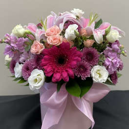 Pink and white mixed flower arrangement in a round pink box with ribbon
