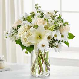 White flowers and roses arranged in a clear glass vase
