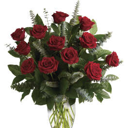 Red roses arranged in a clear glass vase with eucalyptus