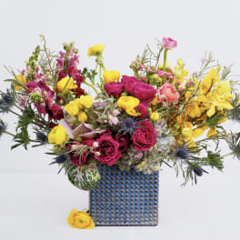 Bright mixed bouquet in a blue patterned vase with yellow and pink flowers