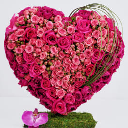 Heart-shaped bouquet of pink roses with a purple orchid accent