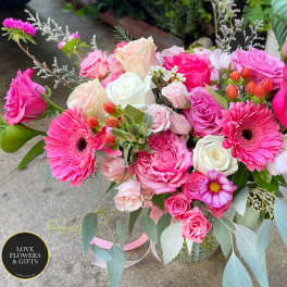 Vase arrangement of hot pink and white roses with pink gerbera daisies and mixed blooms.
