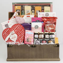 Gift basket filled with chocolates, crackers, jams, and popcorn in a wooden chest
