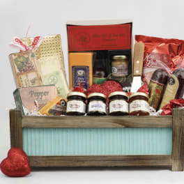 Gift basket with crackers, jams, and chocolates in a wooden crate