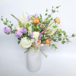 Mixed bouquet of pastel flowers in a white vase