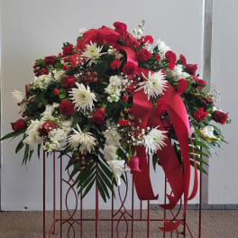 Large red and white floral spray with ribbon on a stand