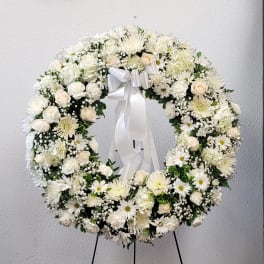 White floral wreath with a ribbon bow on a stand