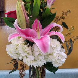 Pink lily and red rose arrangement in a clear glass vase