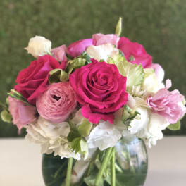 Pink and white bouquet of roses, ranunculus, and hydrangeas in a glass vase