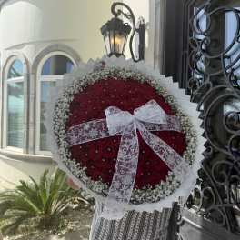 Large round bouquet of red roses with a white lace bow