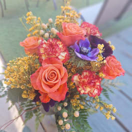 Bouquet of coral roses and purple flowers with yellow filler