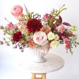 Mixed pink and red floral arrangement in a white vase