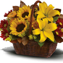 Basket of yellow lilies, sunflowers, and red daisies
