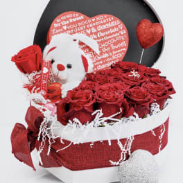 Red roses in a gift box with a teddy bear and heart decorations