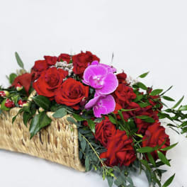 Red roses and pink orchids in a woven basket
