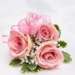 Small cluster of pink roses with white filler flowers and a pink ribbon bow