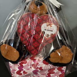 Gift basket with a teddy bear and heart-shaped chocolate box wrapped in cellophane