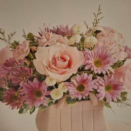 Pink roses and daisies arranged in a blush vase