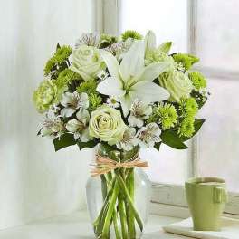 White lilies and pale roses in a clear glass vase