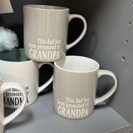 Gray ceramic mugs with the text "This dad has been promoted to GRANDPA"