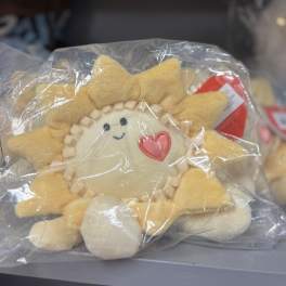 Plush sun-shaped toy in a clear plastic bag with a heart patch