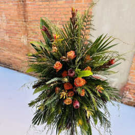 Tall tropical floral spray with orange roses and mixed greenery on a stand