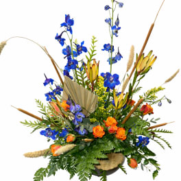 Blue and orange floral arrangement with tall stems in a low container
