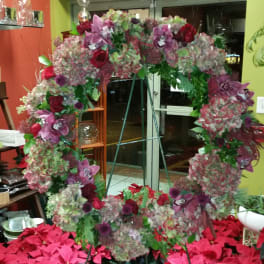 Large floral wreath with pink, purple, and red blooms on a stand