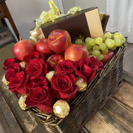 Basket of red roses, apples, grapes, and chocolates with a gift box