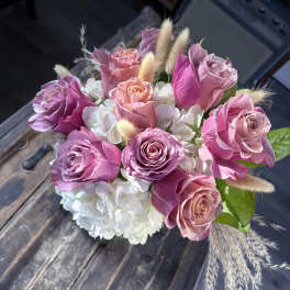 Pink and lavender roses with white hydrangeas in a compact bouquet