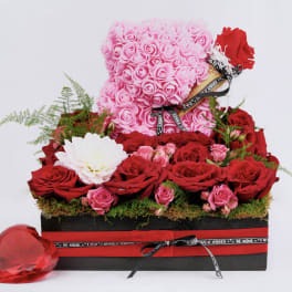 Pink rose teddy bear with red roses in a gift box and a red heart