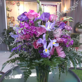 Tall bouquet of purple and pink flowers in a glass vase