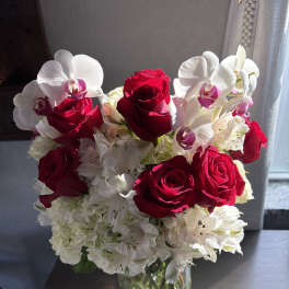 Red roses and white orchids in a clear glass vase