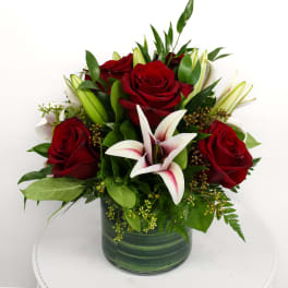 Red roses and white lilies in a green glass vase